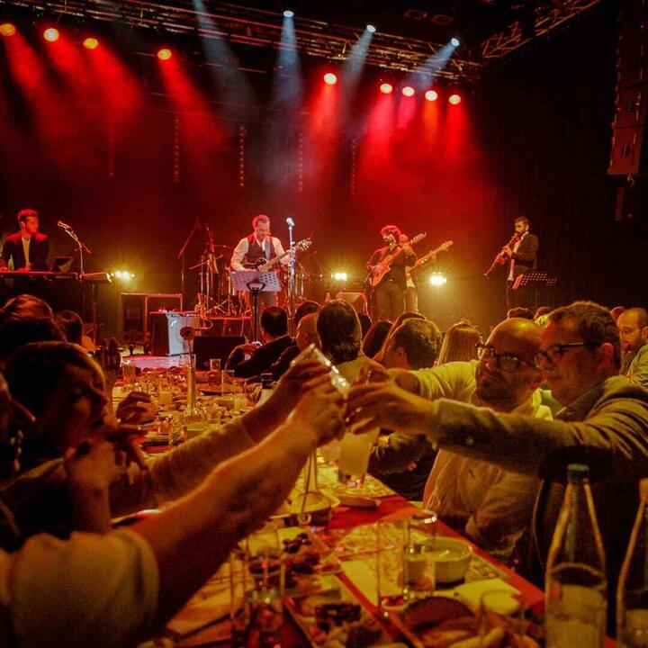 mensen toasten feestelijk, op de achtergrond een band op het podium